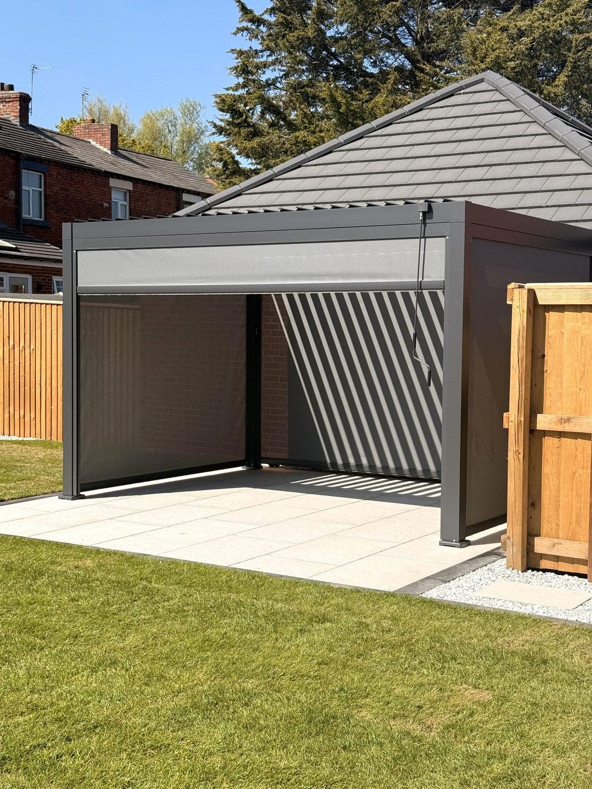 Charcoal louvred pergola and porcelain patio by Renovations of Cheshire